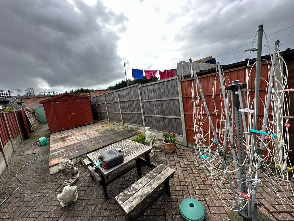 Cluttered back garden before clearance — weathered furniture and stored items